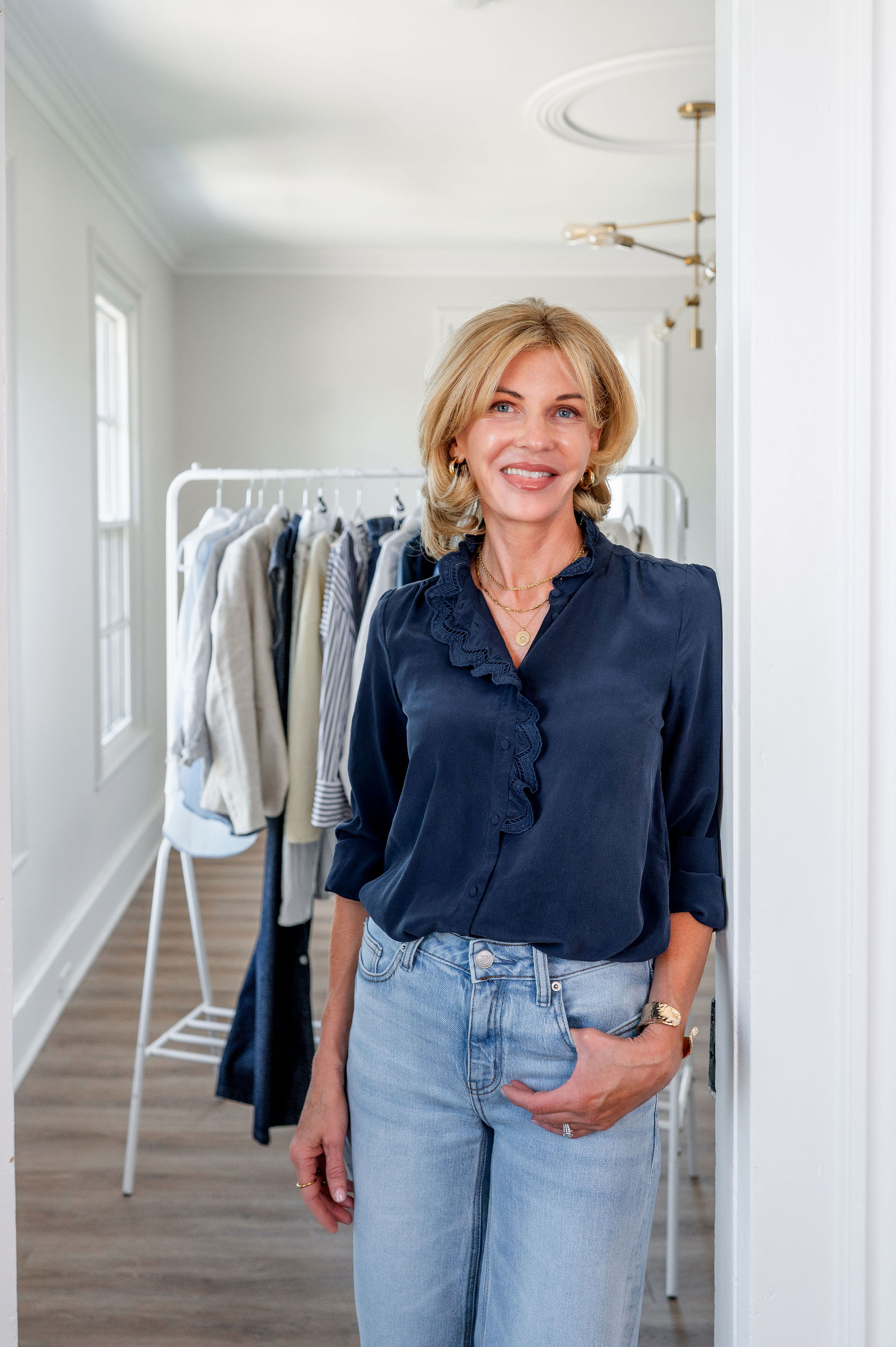 Laura standing beside a styled clothing rail in her studio